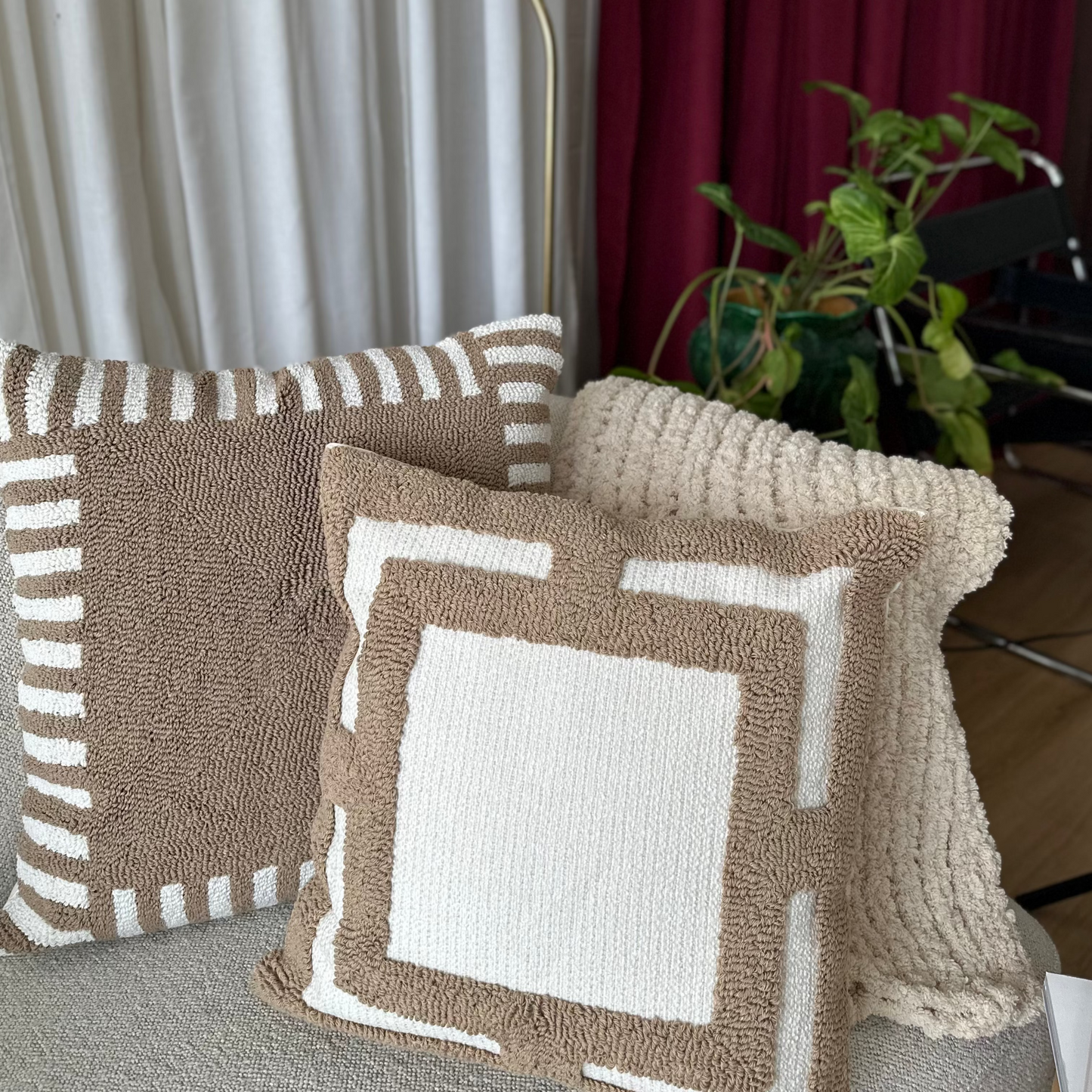 Decorative pillows on a sofa with a lamp and curtains in the background
