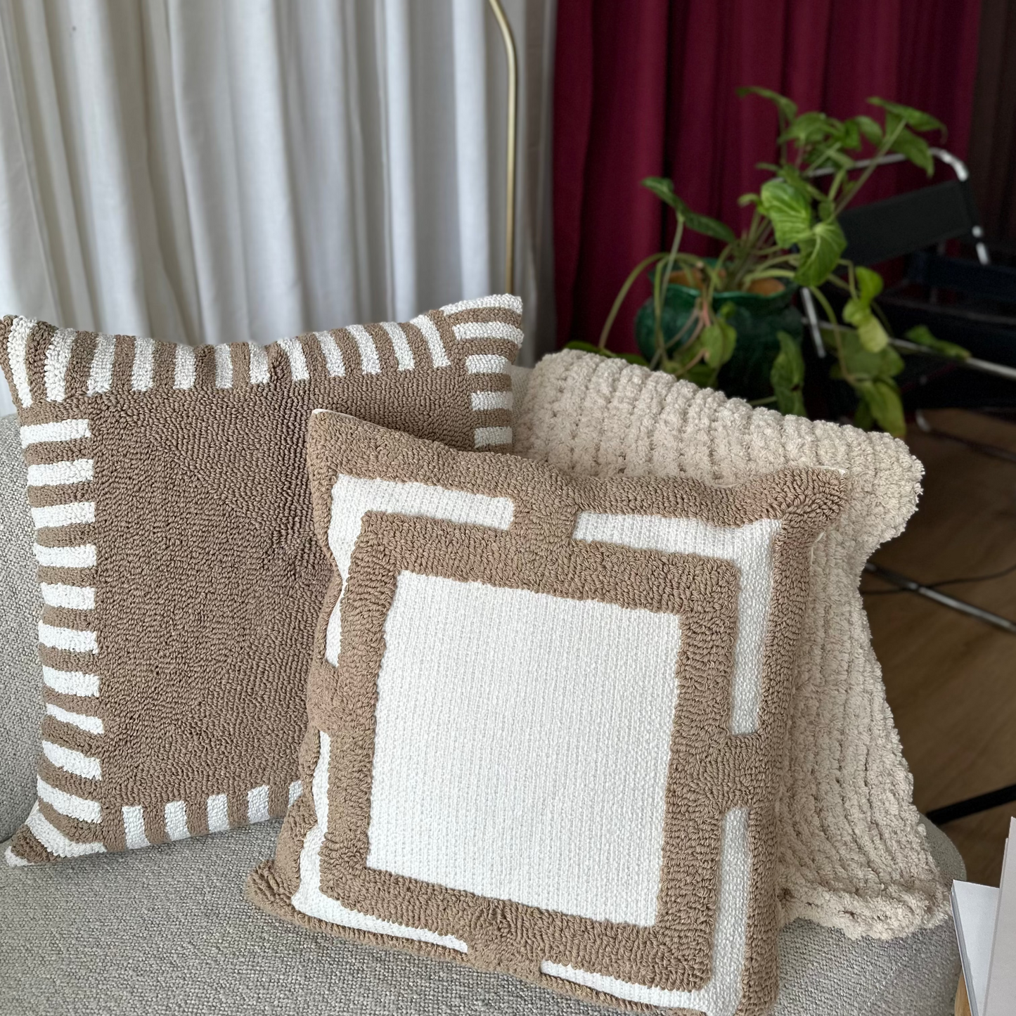 Decorative pillows on a sofa with a lamp and curtains in the background