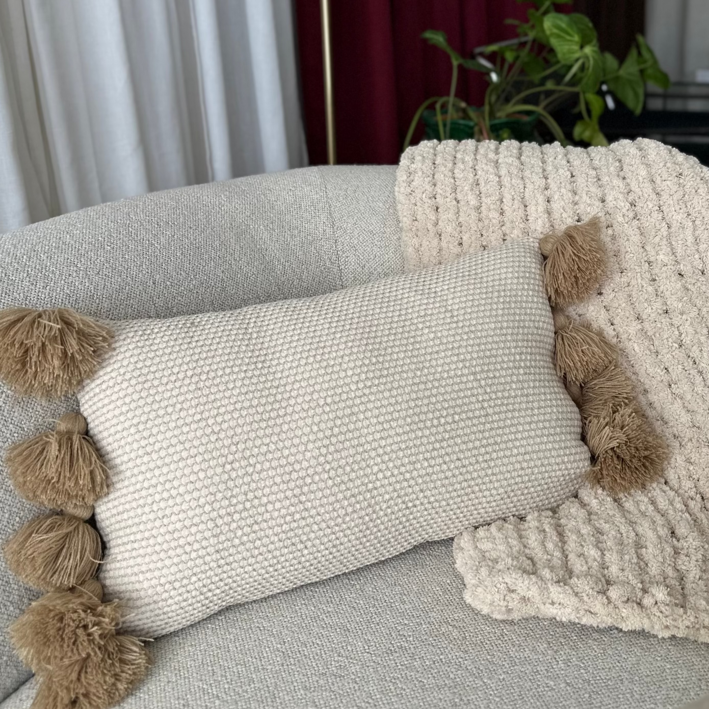 Decorative pillows with pom-poms on a sofa in a living room setting.