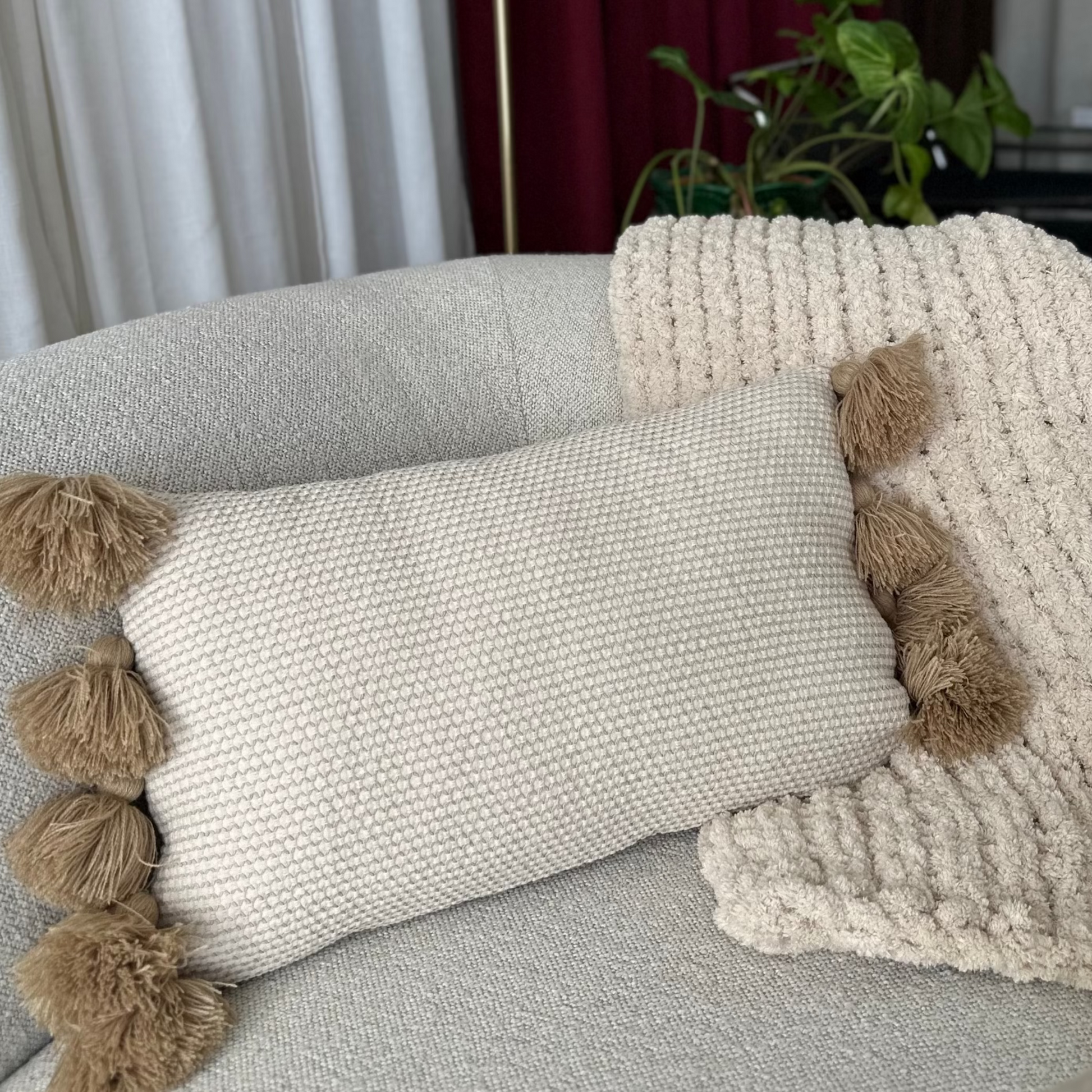 Decorative pillows with pom-poms on a sofa in a living room setting.